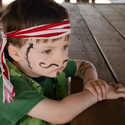 A kid wearing makeup and dressed as a pirate