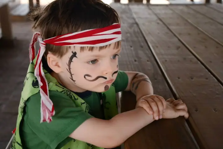 A kid wearing makeup and dressed as a pirate
