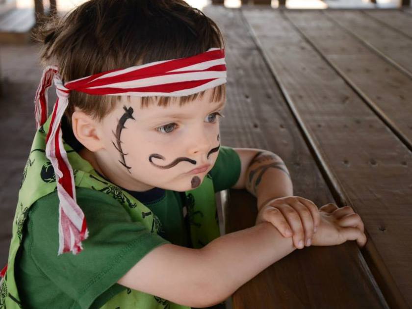 A kid wearing makeup and dressed as a pirate